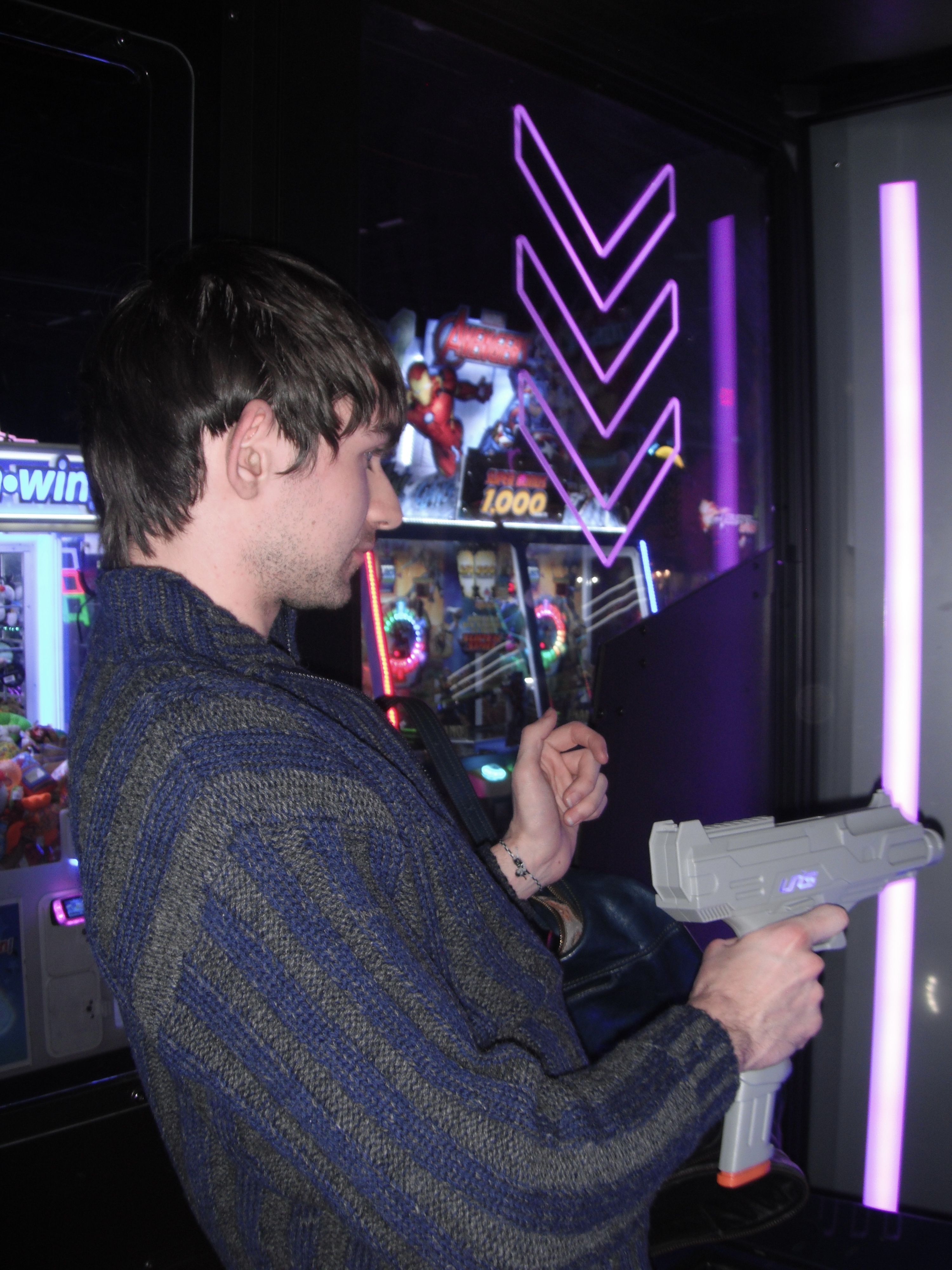 Man at an arcade shooting a toy gun at the game