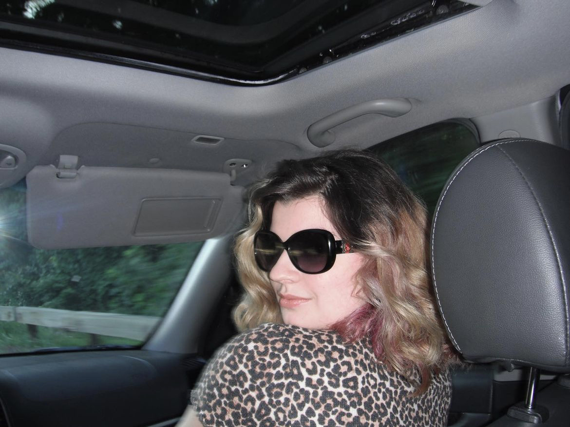 Mary turning around in the fron seat in sunglasses