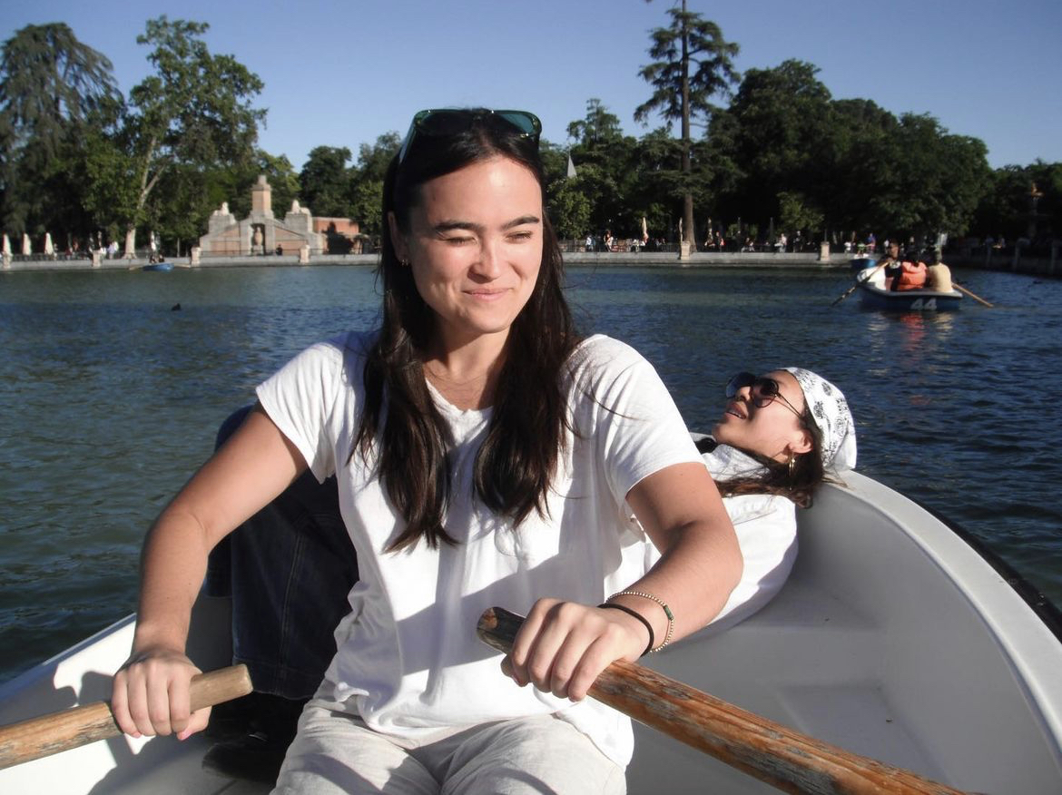 Ras rowing a boat with Maddy laying in the background