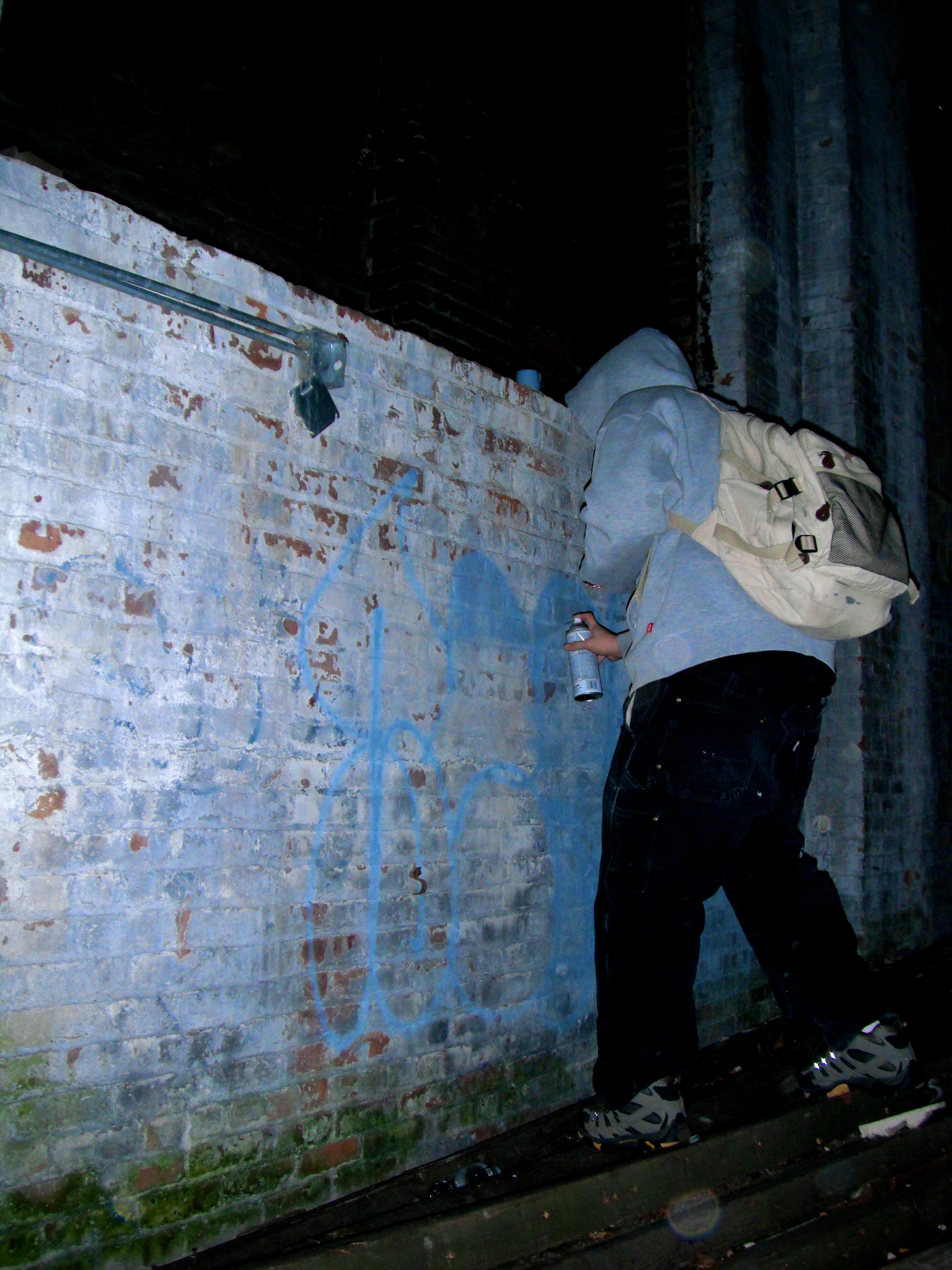 Man in blue spray painting a wall